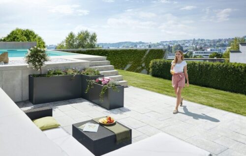 Das biohort DaVinci in dunkelgrau metallic auf einer grossen Terrasse mit Pool und Gartenlounge. Softub Schweiz