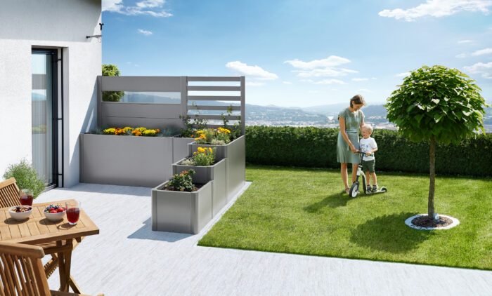 Das biohort DaVinci mit Rankgitter und Sichtschutz in silber metallic. Das Hochbeet steht auf einer Terrasse. Die Beete sind mit Blumen gefüllt.