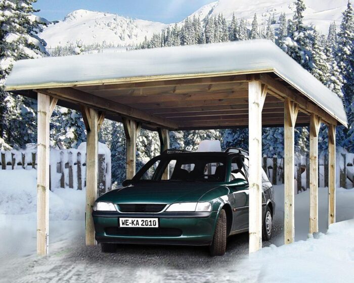 Wooden carport with four posts on each side. Snow covered in the mountains. Green car is parked under the carport.